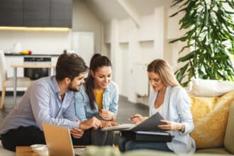 Paar lässt sich zu Hause von einer Beraterin zur Altersvorsorge und zum benötigten Geld im Alter beraten